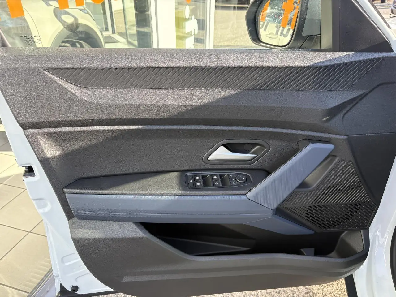 Vue intérieure de la porte avant gauche du Dacia Duster blanc métallisé avec commandes de vitres et accoudoir Denim Bleu.