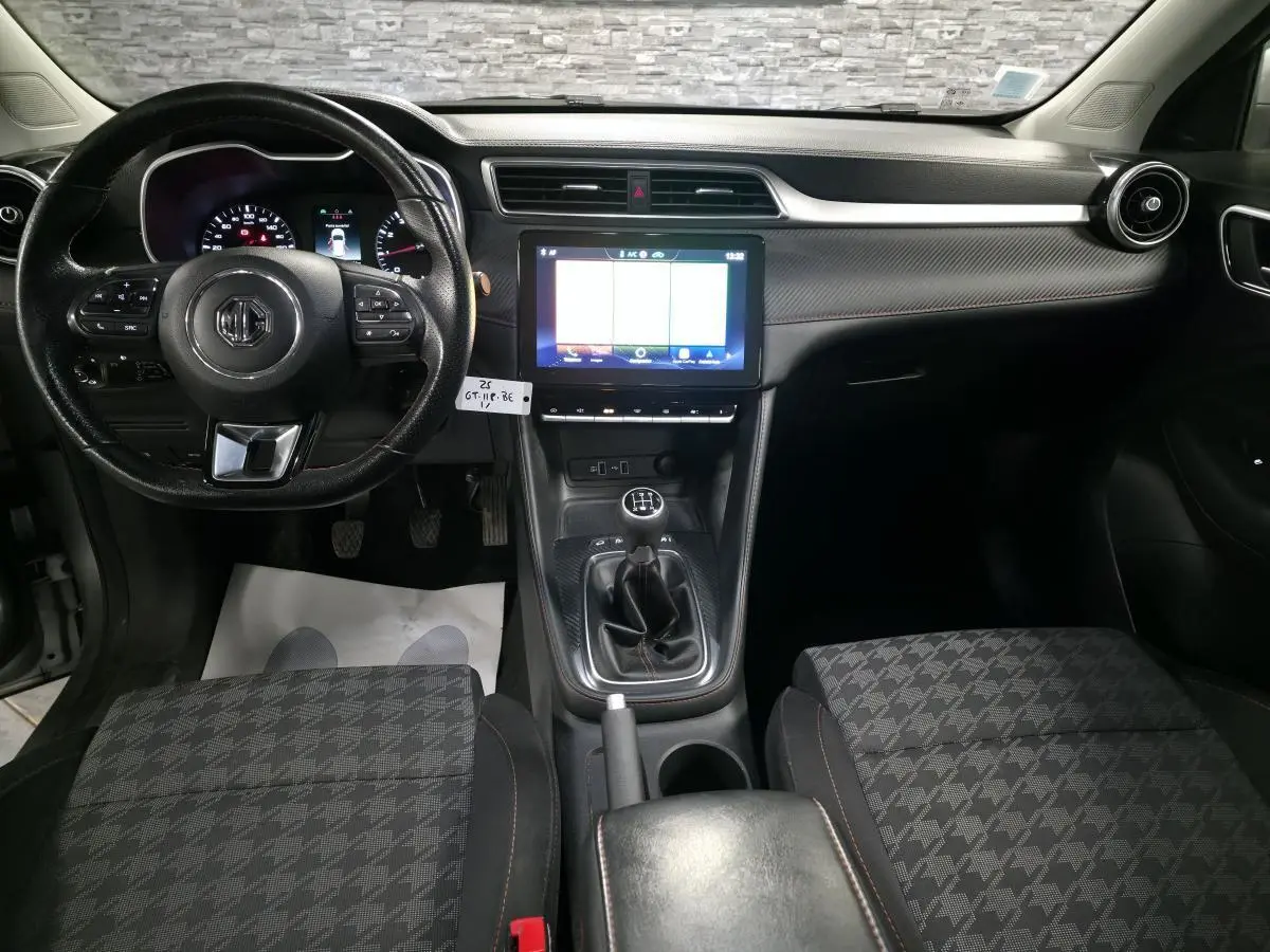 Intérieur avant du MG ZS gris 2023, vue centrée sur le volant cuir, écran tactile et levier de vitesse manuel.
