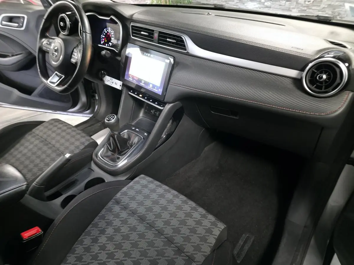 Intérieur côté passager du MG ZS gris 2023, montrant la console centrale avec écran tactile et levier de vitesses manuel.