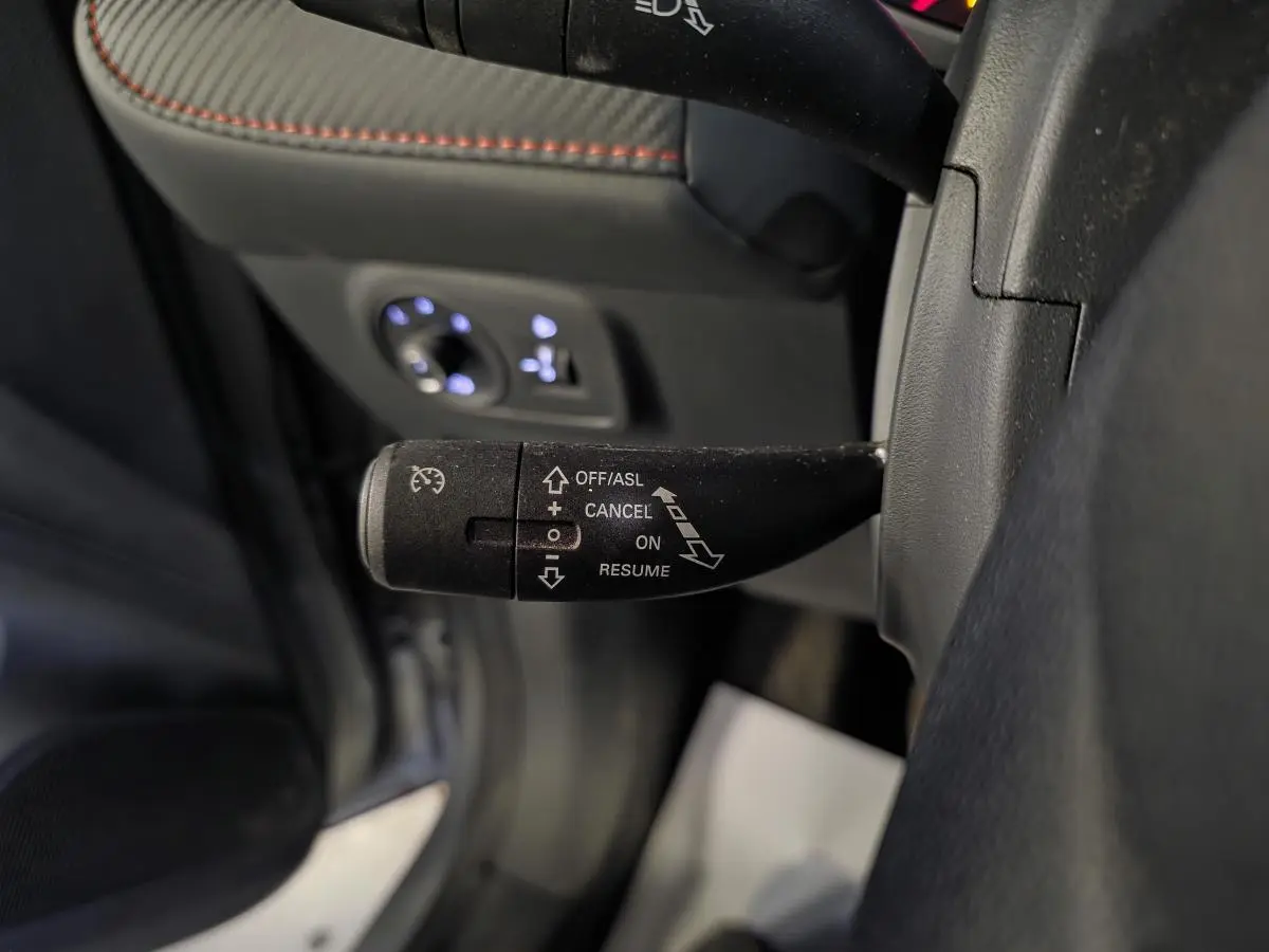 Gros plan sur la manette de régulateur de vitesse côté gauche du volant dans l’habitacle gris du MG ZS 2023.