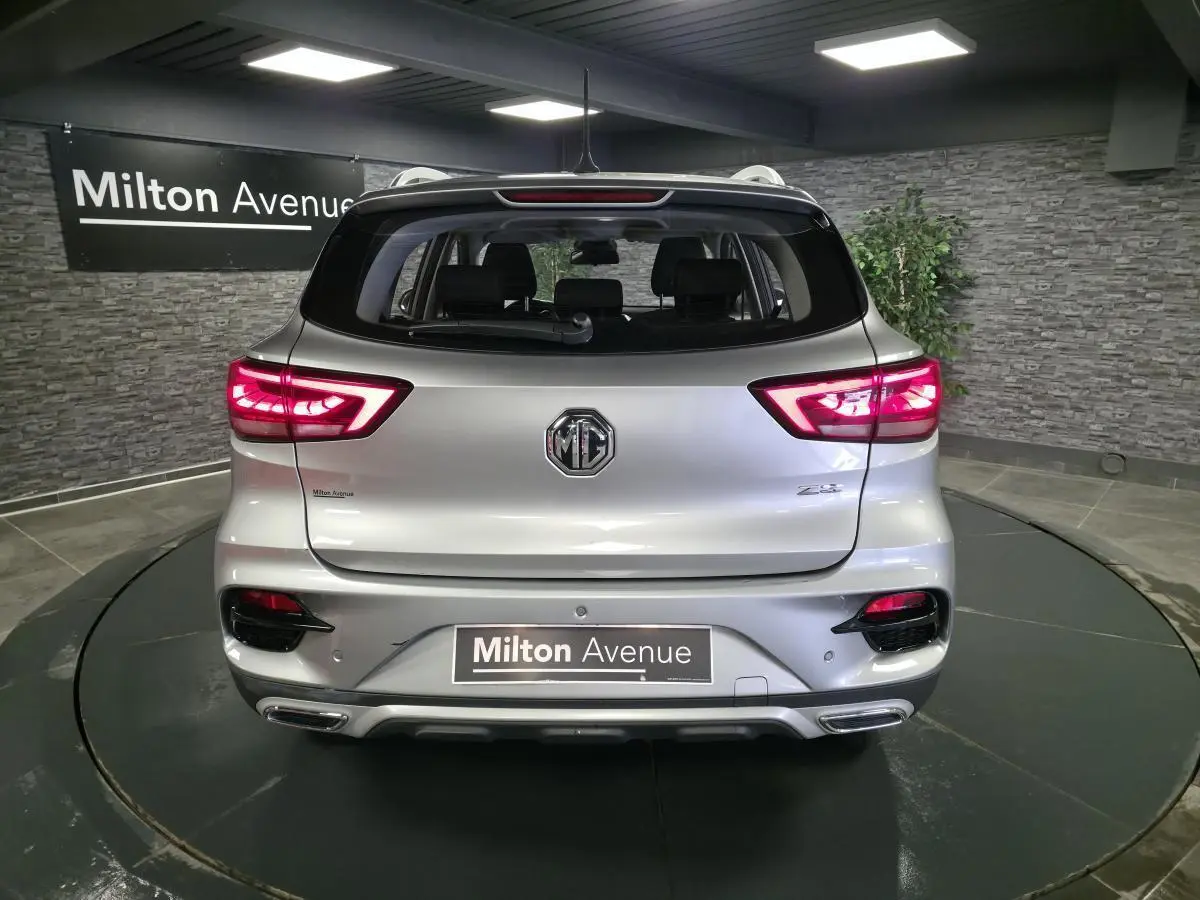 Vue arrière d'un MG ZS gris métallisé 2023 avec feux arrière LED allumés dans un showroom.