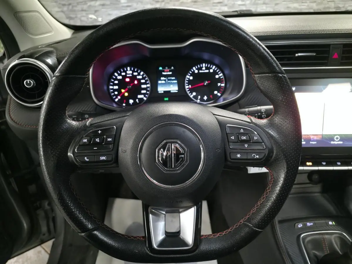 Vue intérieure centrée sur le volant cuir noir du MG ZS 2023 avec commandes intégrées et tableau de bord lumineux.