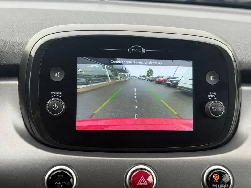 Écran de caméra de recul du Fiat 500X 2024 affichant une vue arrière avec lignes de guidage et pare-chocs rouge pastel visible.
