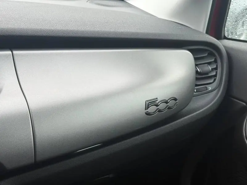 Vue intérieure côté passager du tableau de bord gris avec logo 500 du FIAT 500X 2024 Rouge Passione pastel.