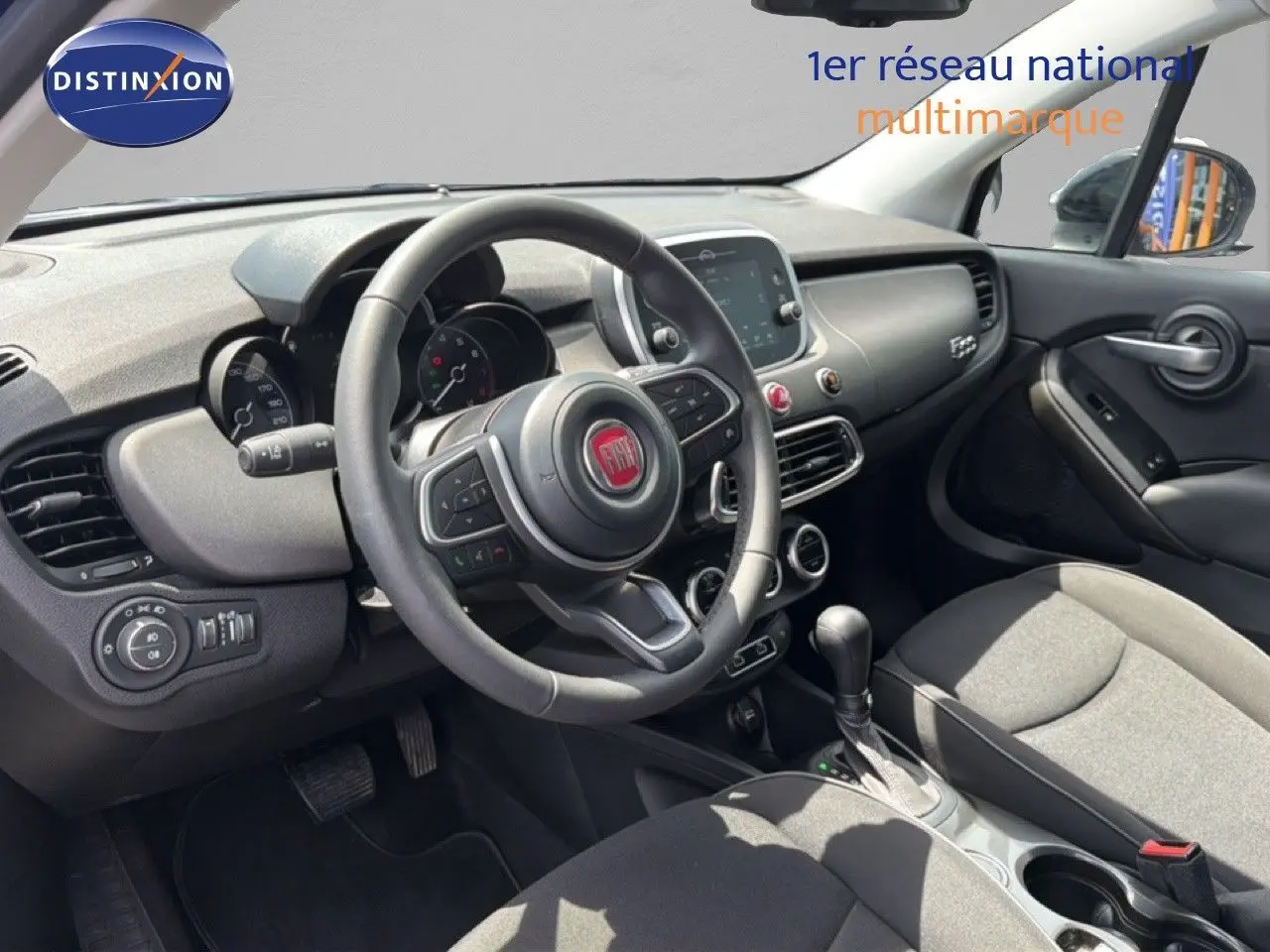 Vue intérieure côté conducteur du tableau de bord et volant du Fiat 500X 2024, finition moderne et épurée.