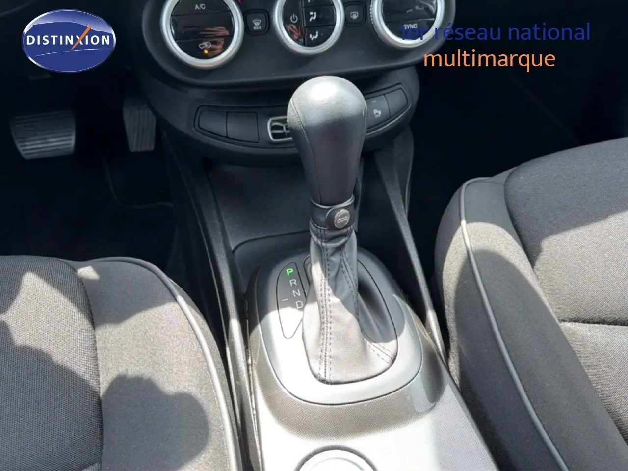 Gros plan sur la console centrale et levier de vitesse automatique d’une Fiat 500X, intérieur tissu gris.