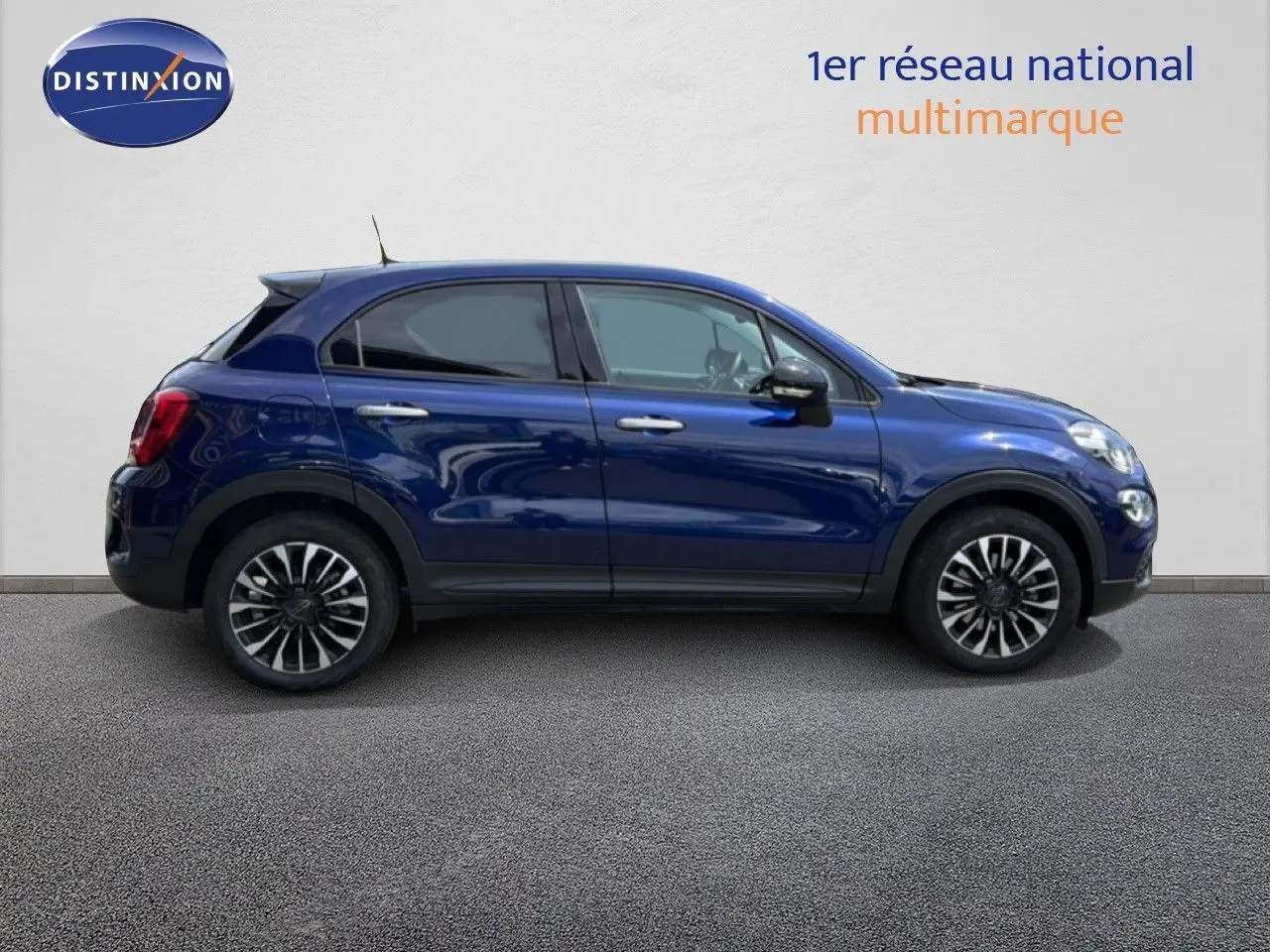 Vue de profil côté gauche d'une FIAT 500X 2024 bleu Venezia avec jantes alliage bi-ton et vitres teintées.