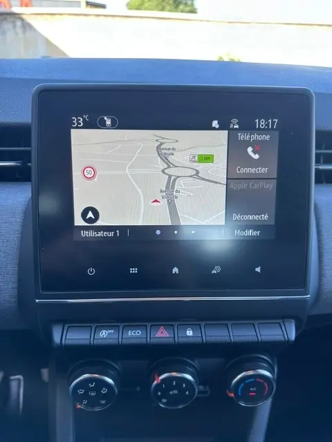 Écran tactile central de la Renault Clio V diesel 2025 montrant la navigation GPS et les commandes de climatisation manuelle.