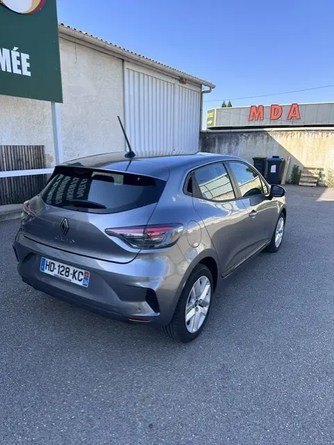 Vue 3/4 arrière droite d'une Renault Clio gris métallisé 2025 avec vitres surteintées et feux arrière LED.