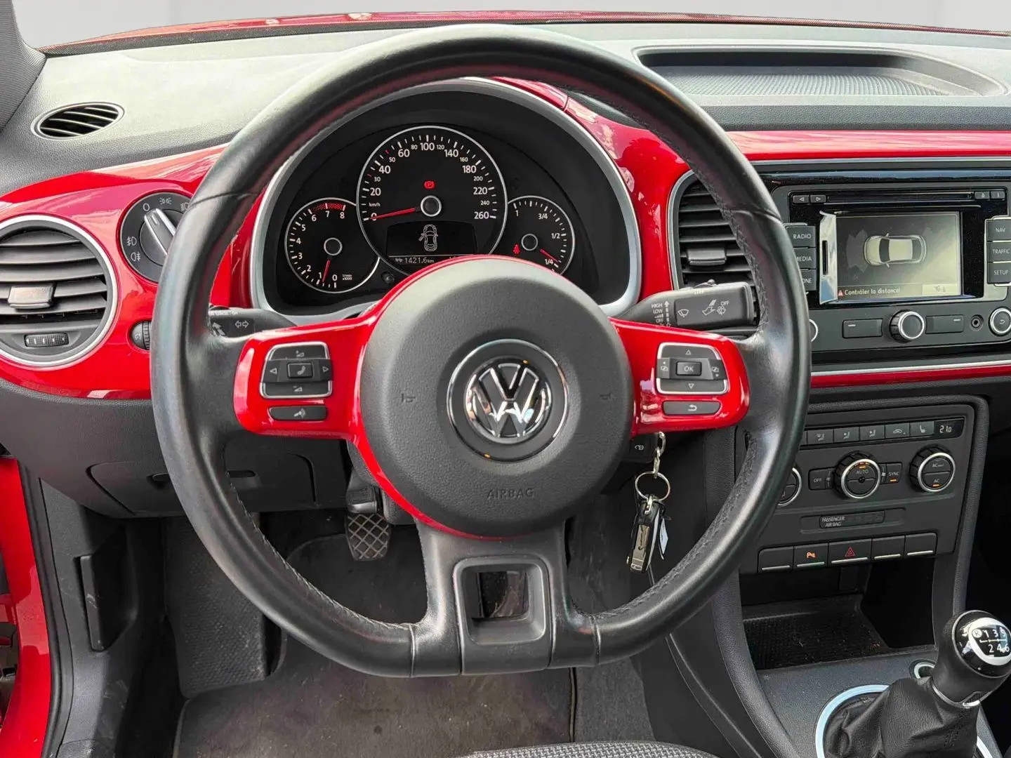 Vue intérieure du volant cuir noir et rouge de la Volkswagen Coccinelle 2012 avec tableau de bord et levier de vitesse manuel.