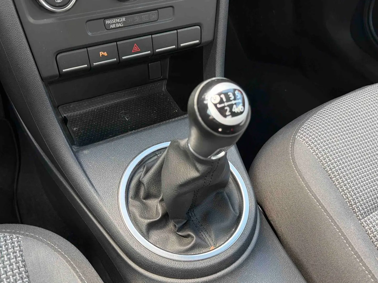 Gros plan sur le levier de vitesses manuel en cuir de la Volkswagen Coccinelle, entouré de la console centrale noire.