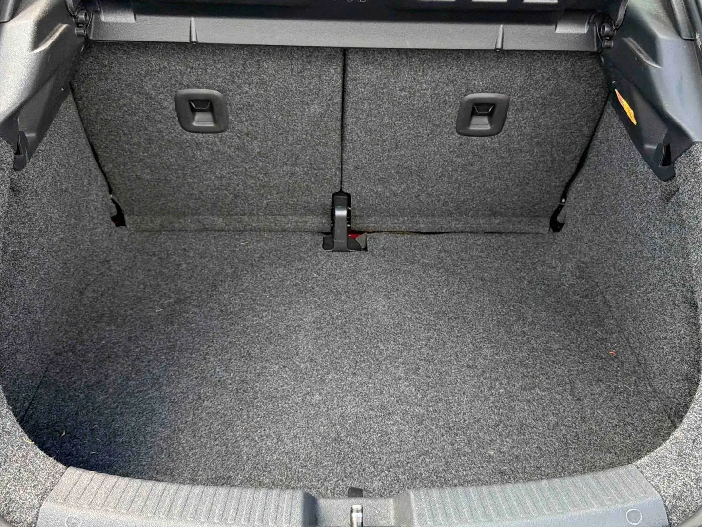 Coffre vide vu de face, revêtement gris, intérieur spacieux de la Volkswagen Coccinelle rouge 2012.