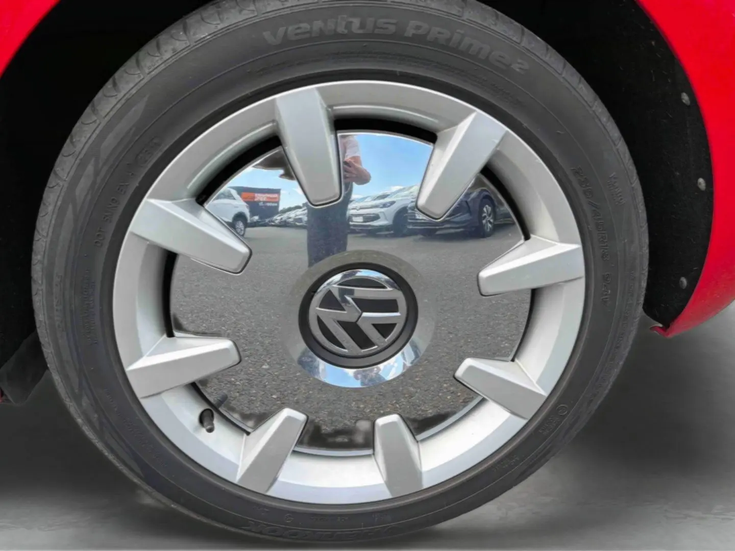 Gros plan sur la jante 18 pouces argentée avec logo Volkswagen, partie droite d'une Volkswagen Coccinelle rouge.