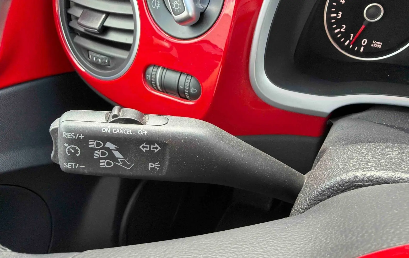 Gros plan sur le commodo de régulateur de vitesse dans l’habitacle rouge vif d’une Volkswagen Coccinelle 2012.