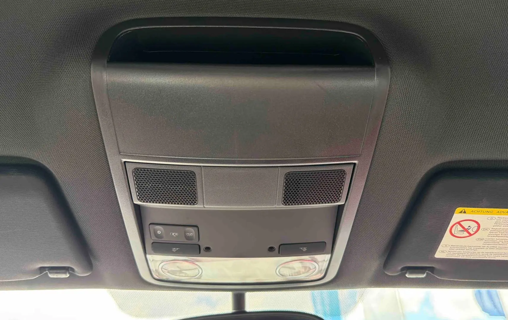 Vue intérieure du plafonnier avant de la Volkswagen Coccinelle rouge, montrant les commandes d’éclairage et les haut-parleurs intégrés.
