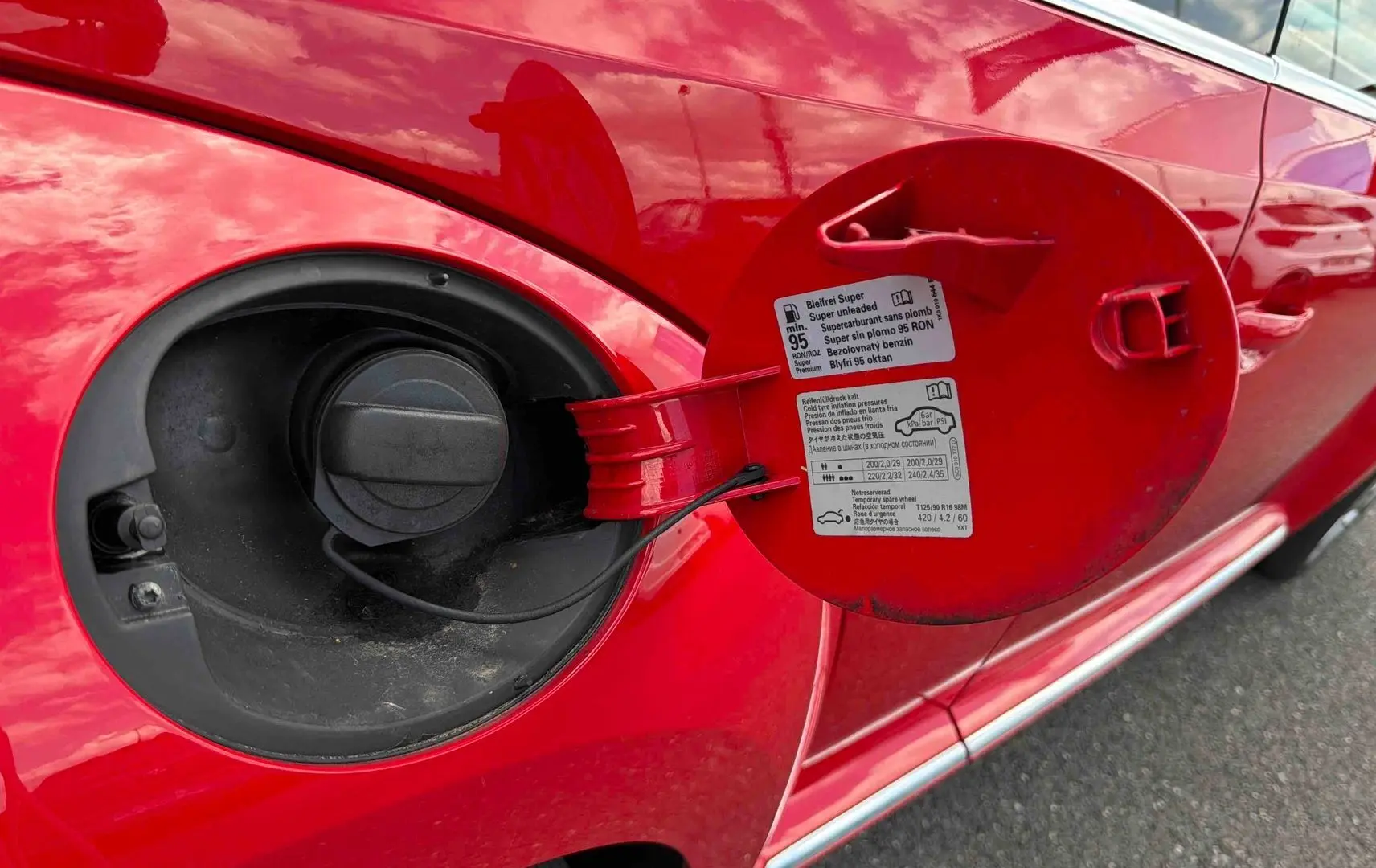 Vue rapprochée du bouchon de réservoir ouvert sur le côté gauche d’une Volkswagen Coccinelle rouge Tornade.