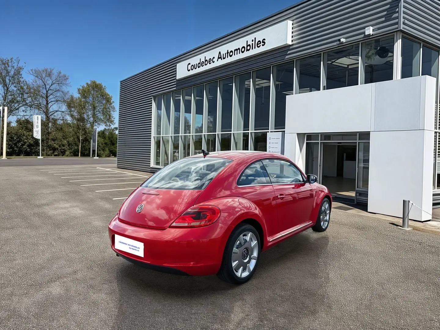 Volkswagen Coccinelle rouge vue 3/4 arrière droit, avec jantes 18 pouces et feux arrière LED, devant un showroom.