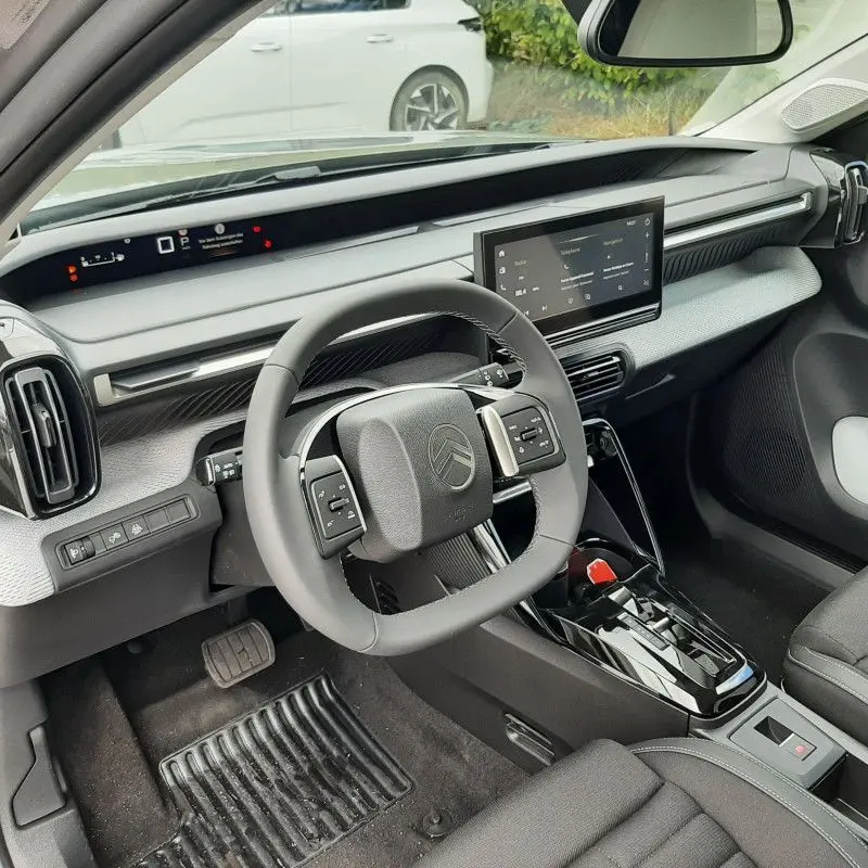 Vue intérieure côté conducteur du Citroën C3 Aircross hybride 2026, montrant le volant carré et l'écran tactile central.