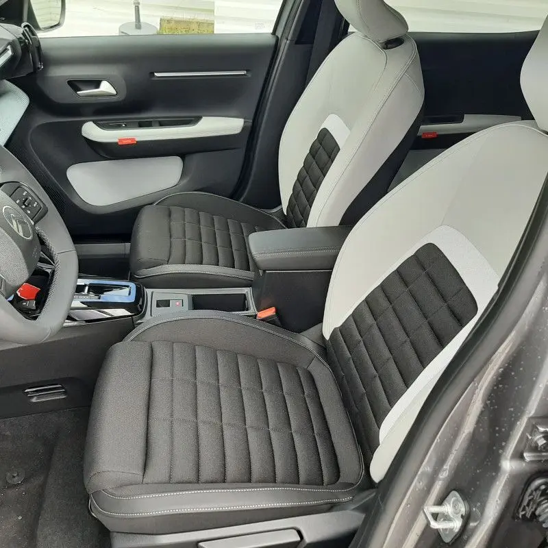 Vue intérieure côté conducteur de la Citroën C3 Aircross hybride 2026, sièges bicolores noir et beige, console centrale visible.