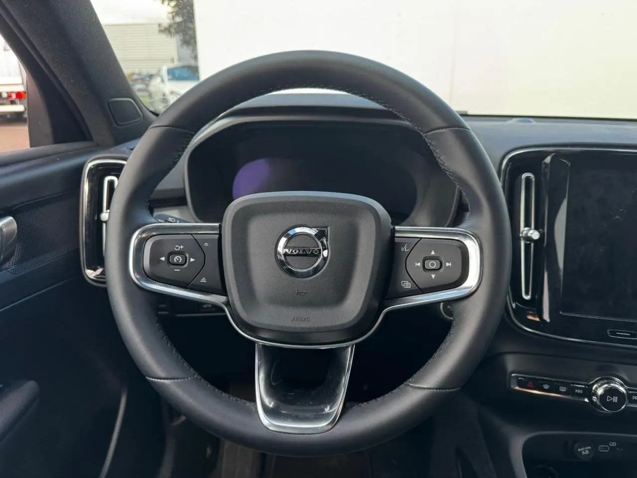 Volant en cuir noir de Volvo XC40 2024 vu de face avec commandes intégrées et tableau de bord digital.