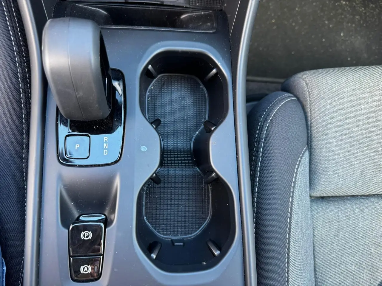 Vue plongeante sur la console centrale noire du Volvo XC40 avec levier de vitesses automatique et porte-gobelets.