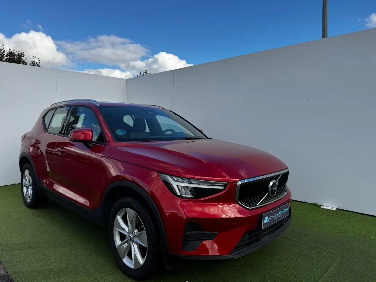 Volvo XC40 Fusion Red en 3/4 avant droit, avec jantes alliage 18 pouces et calandre noire distinctive.