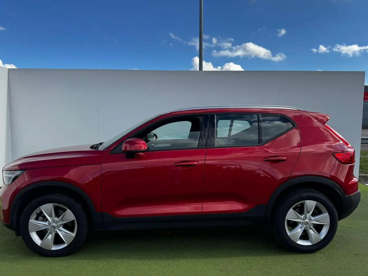 Profil côté gauche du Volvo XC40 2024 en rouge Fusion avec jantes alliage 18 pouces sur fond clair.