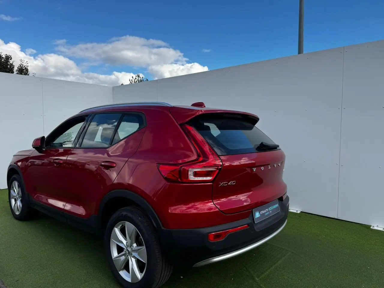 Vue 3/4 arrière droite d'un Volvo XC40 rouge Fusion Metal avec jantes alliage 18 pouces sur fond extérieur.