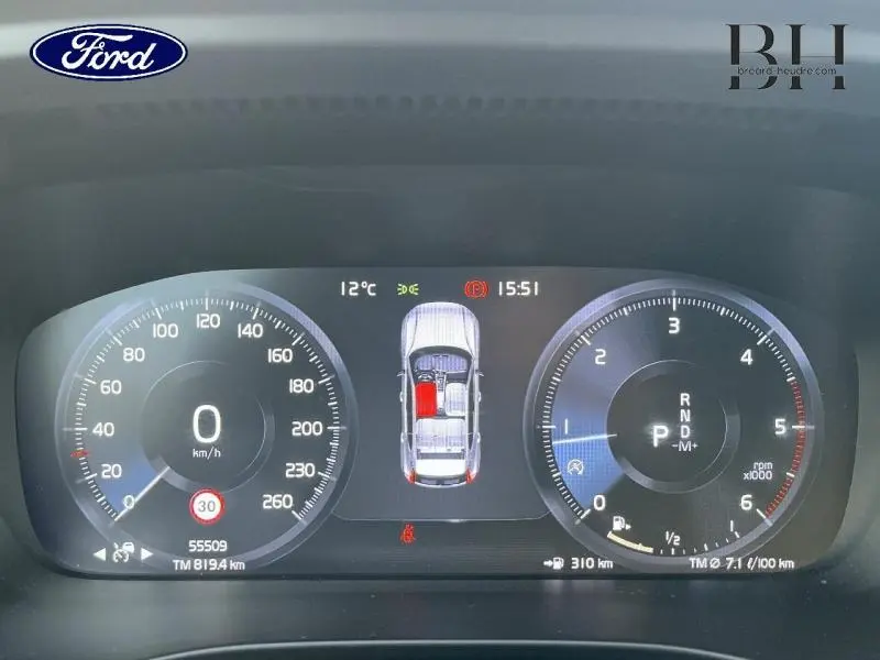 Tableau de bord numérique du Volvo XC40 noir, affichant vitesse, régime moteur et alertes en vue frontale.