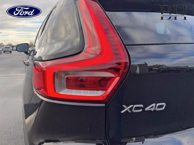Gros plan sur le feu arrière gauche d'un Volvo XC40 noir avec logo et badge modèle visibles sur la carrosserie.