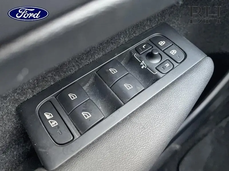 Gros plan sur les commandes des vitres électriques côté gauche d'un Volvo XC40 noir, avec réglages des rétroviseurs.