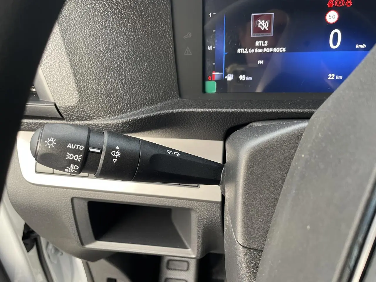 Gros plan sur la manette de clignotants et le combiné numérique bleu du tableau de bord de l'Opel Vivaro blanc.