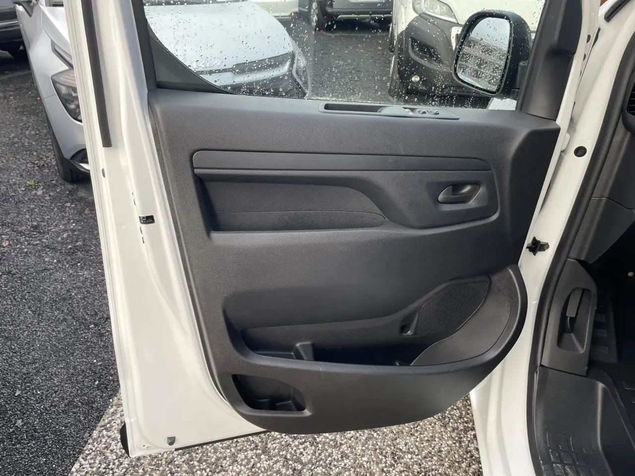 Vue intérieure de la porte avant gauche blanche d’un Opel Vivaro 2024 avec panneau de porte noir et poignée intégrée.