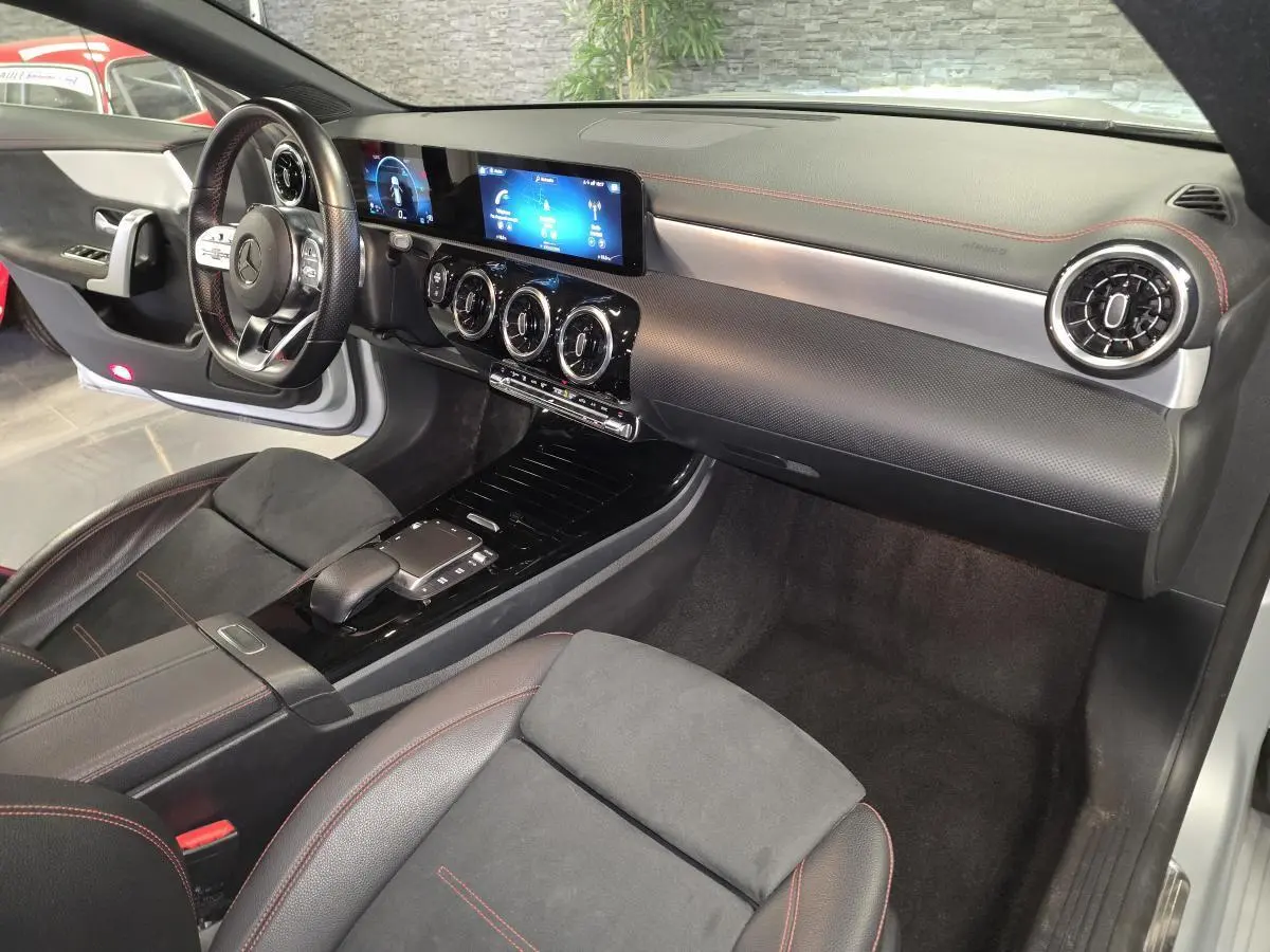 Vue intérieure côté passager de la Mercedes CLA Shooting Brake 200 AMG Line 2020 avec tableau de bord noir et surpiqûres rouges.