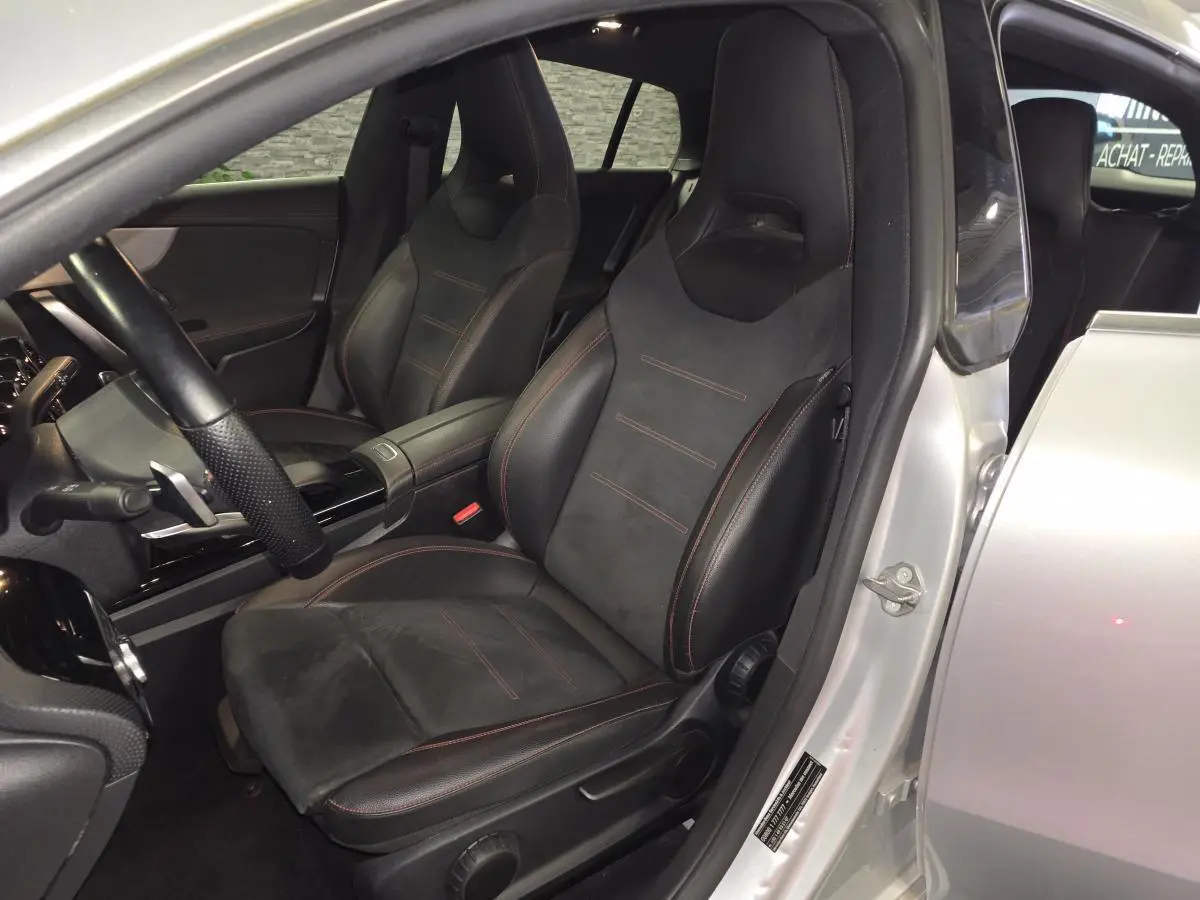 Vue intérieure côté conducteur d'une Mercedes Classe CLA Shooting Brake gris avec sièges sport noirs à surpiqûres rouges.