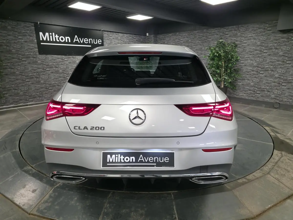 Vue arrière d'une Mercedes CLA 200 gris métallisé avec feux LED allumés et double sortie d'échappement chromée.