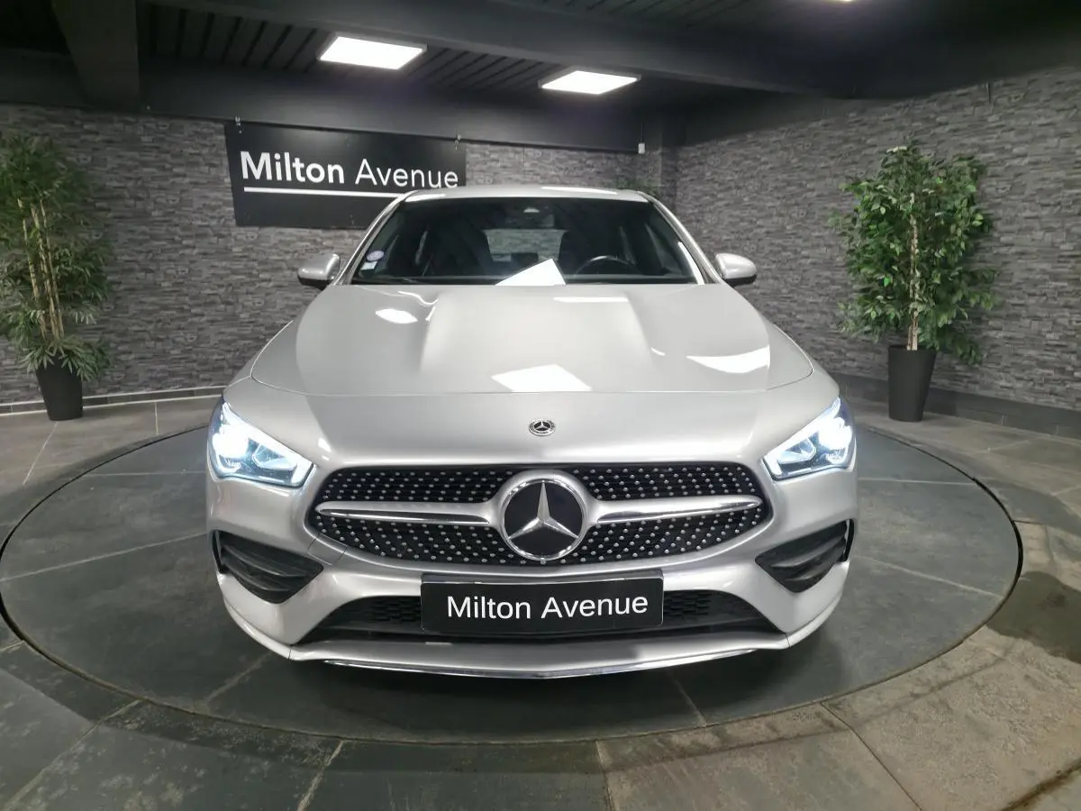 Mercedes Classe CLA Shooting Brake gris métallisé vue de face avec calandre diamant et phares LED allumés.