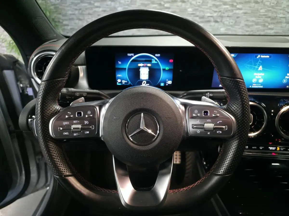 Vue rapprochée du volant sport noir avec surpiqûres rouges et tableau de bord digital de la Mercedes CLA Shooting Brake.