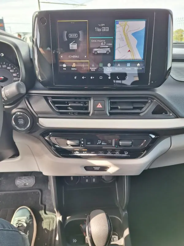 Vue intérieure centrée sur la console centrale de la Suzuki Swift 2025, écran tactile avec navigation et commandes climatisation.