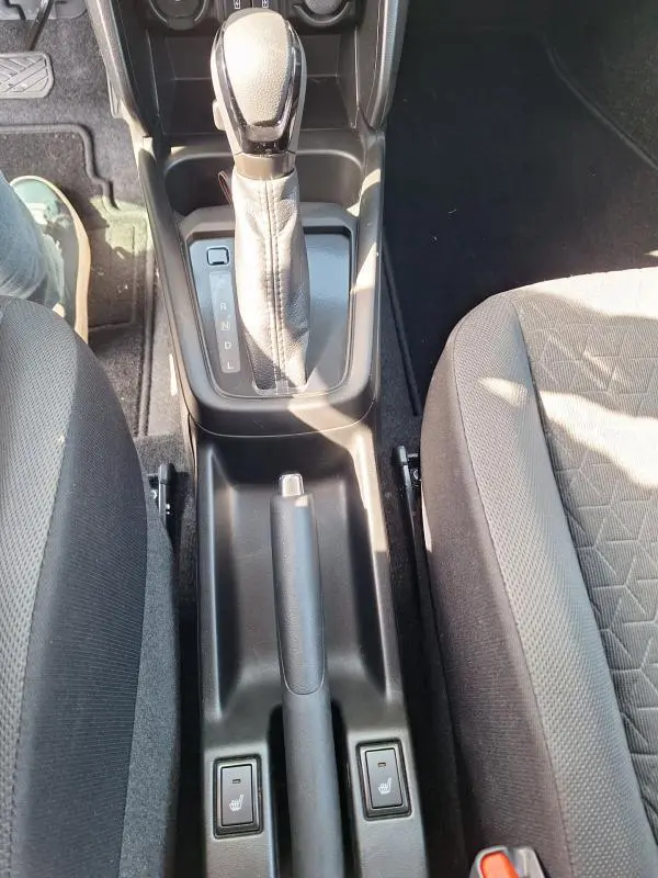 Vue plongeante sur la console centrale de la Suzuki Swift bleu 2025, avec levier de vitesse automatique et sièges tissu gris.