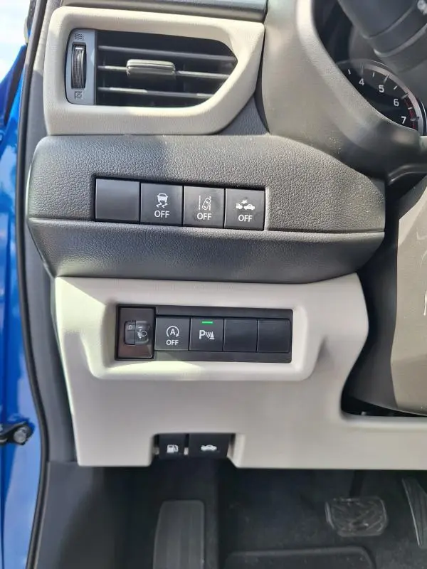 Vue intérieure côté gauche du tableau de bord bleu de la Suzuki Swift 2025, montrant les commandes d'aide à la conduite et ventilation.