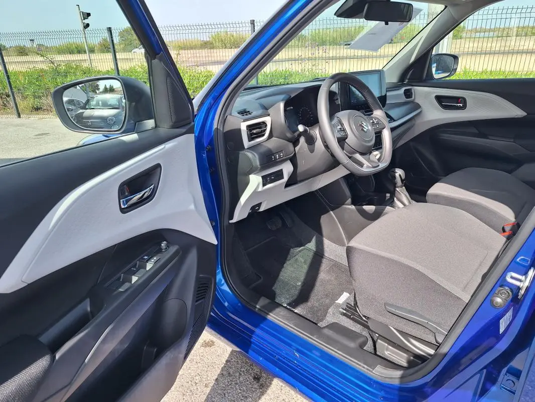 Intérieur côté conducteur d'une Suzuki Swift bleu 2025, montrant le volant, tableau de bord et sièges gris.