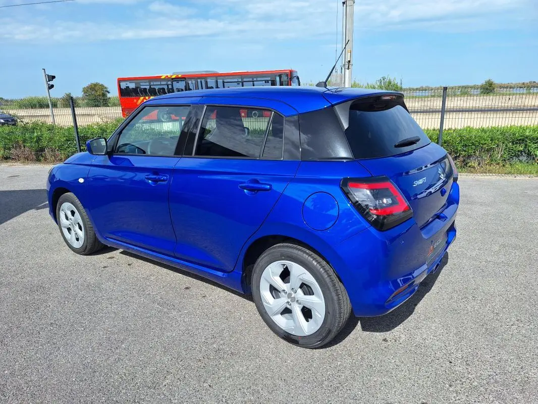 Suzuki Swift 2025 bleu en vue 3/4 arrière droit, avec jantes alliage 16 pouces et vitres teintées.