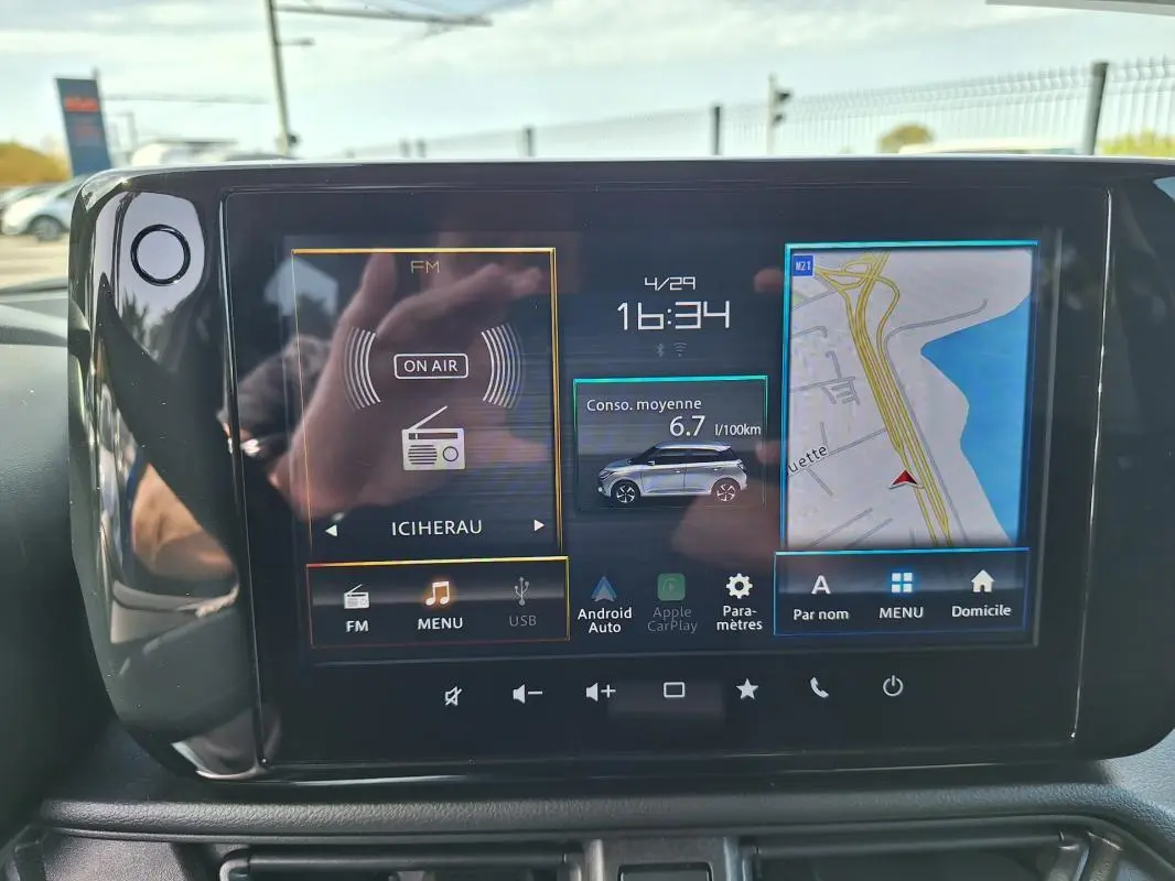 Écran tactile central de la Suzuki Swift 2025 affichant navigation, consommation et radio, intérieur noir.