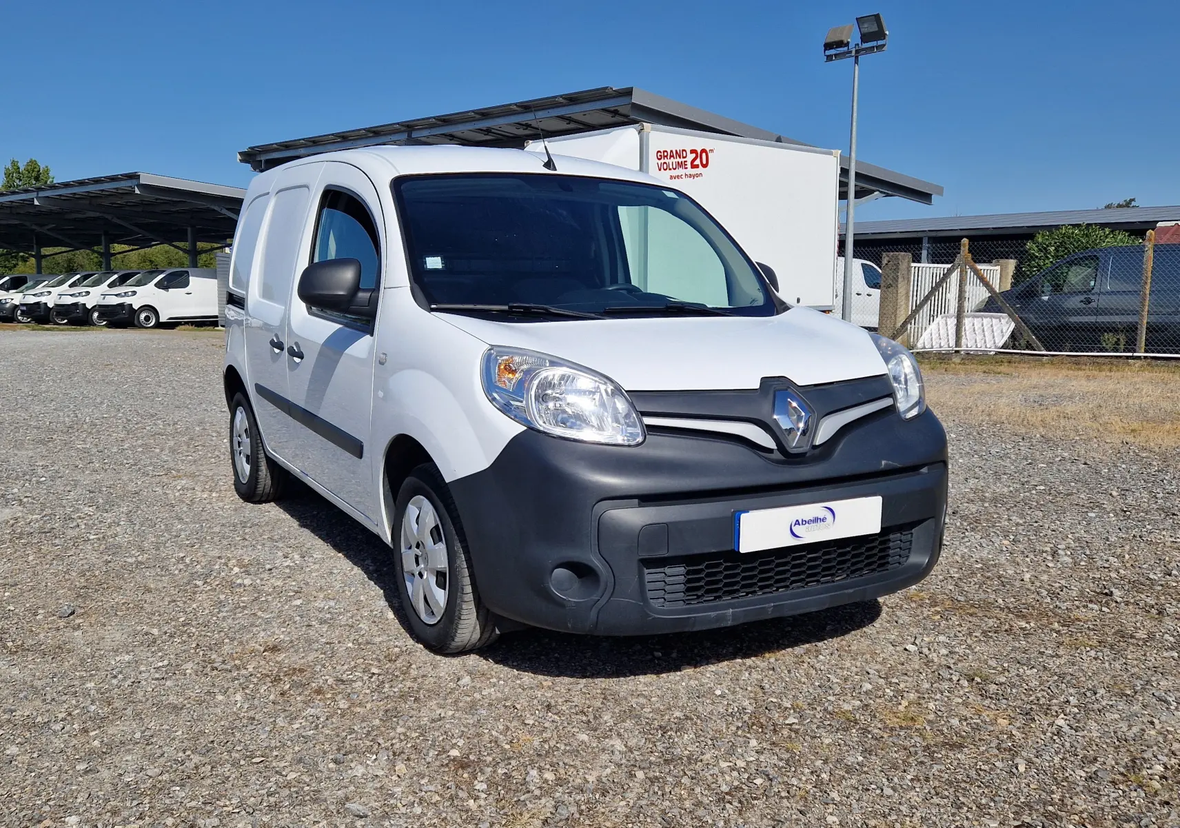 Vue 3/4 avant d’un Renault Kangoo blanc 2021 avec pare-chocs noir mat et calandre marquée du logo Renault.
