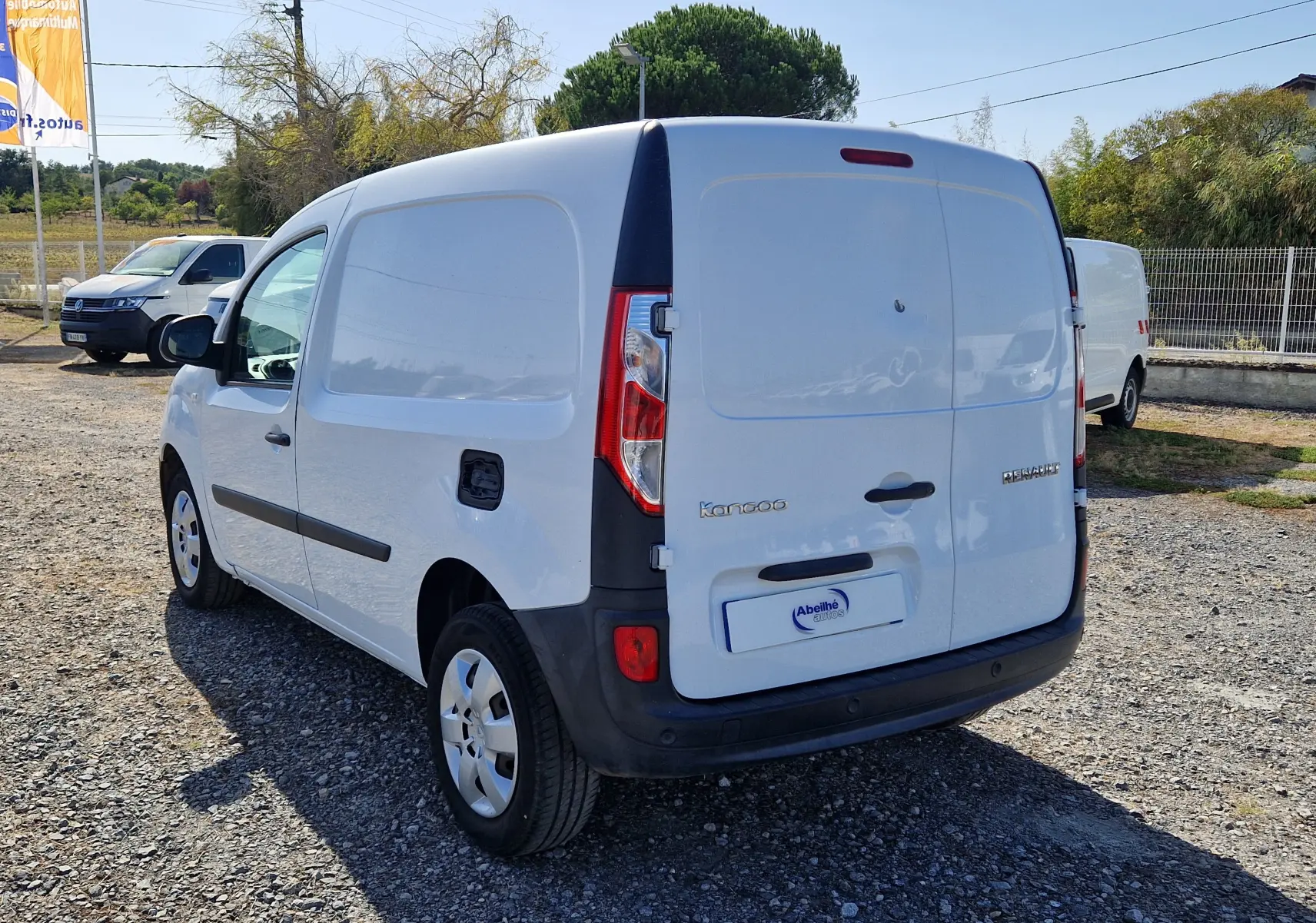 Renault Kangoo blanc vue 3/4 arrière droit, fourgonnette utilitaire avec hayon fermé sur parking extérieur.