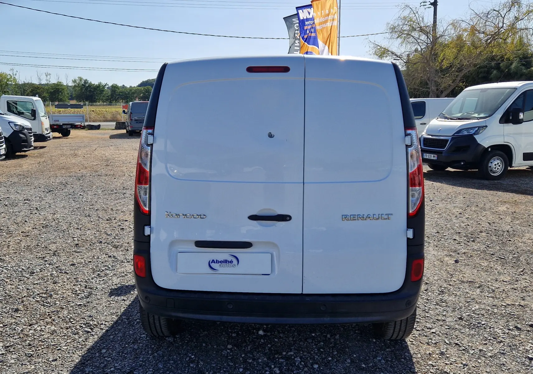 Vue arrière d’un Renault Kangoo blanc 2021 avec portes battantes et logo visible sur un parking extérieur.