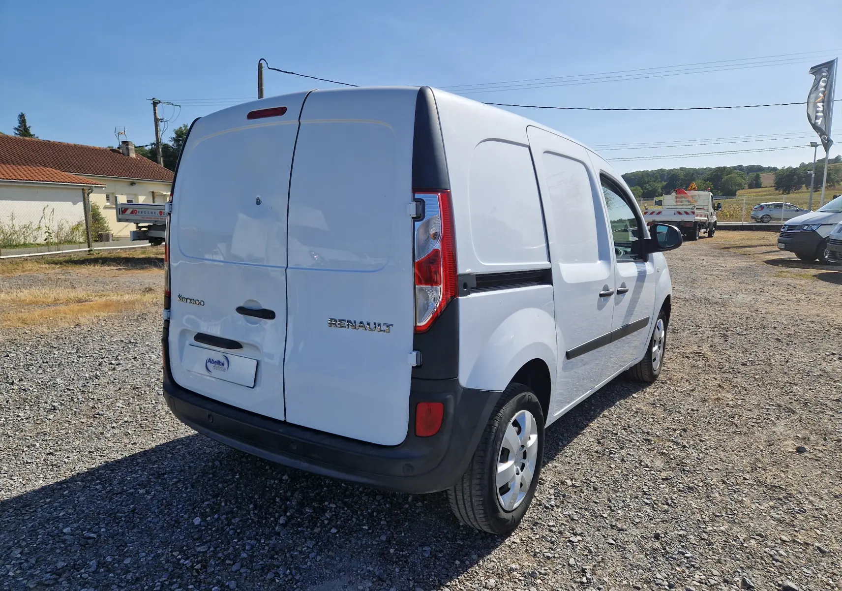 Vue 3/4 arrière droite d’un Renault Kangoo blanc 2021 utilitaire avec portes arrière battantes et protections noires.