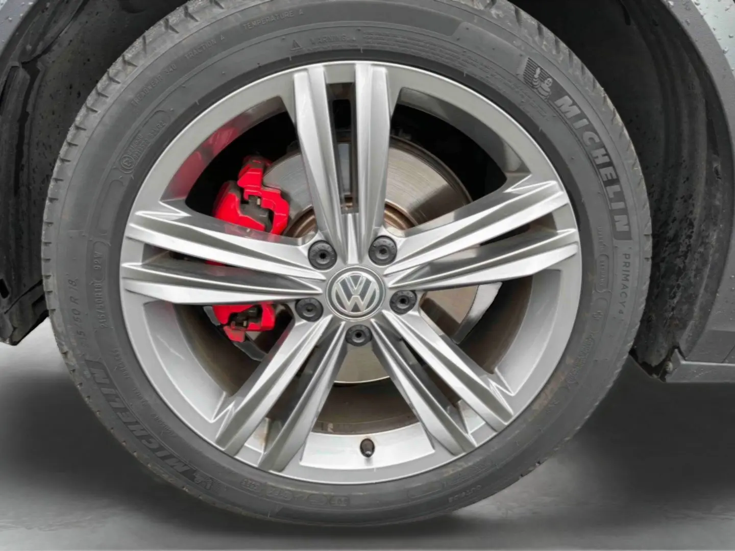 Gros plan sur la jante alliage 18 pouces Nevada gris argent avec étrier de frein rouge du Volkswagen T-Roc gris Indium Metal.