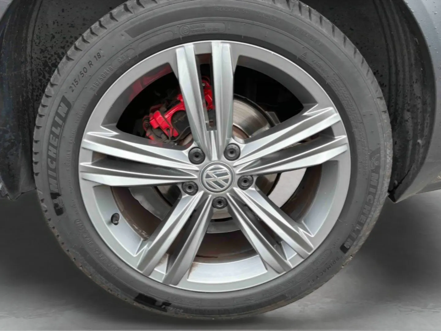 Gros plan sur la jante alliage 18 pouces Nevada argentée avec logo Volkswagen et étrier de frein rouge du T-Roc gris Indium.